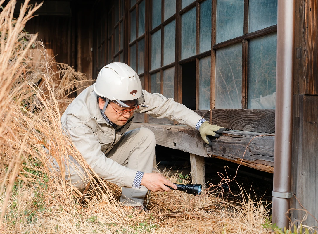 古民家の床下を点検するヘルメット姿の建築専門家