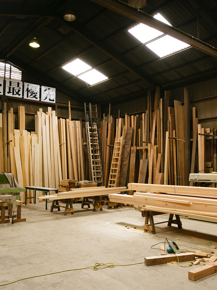 大量の古材が整然と並ぶ木工所の作業場内部