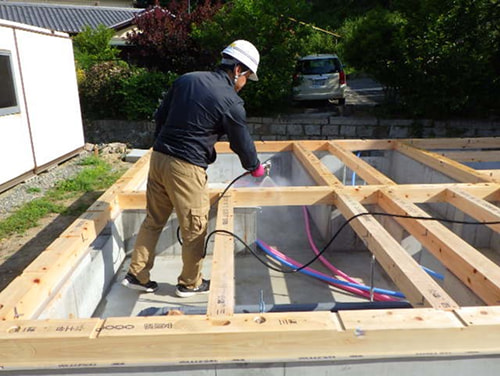 住宅基礎の木部に防蟻処理を行う作業中の様子